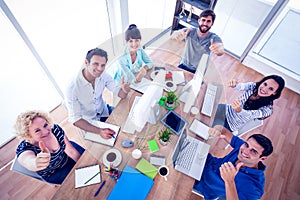 Creative business team gesturing thumbs up in a meeting