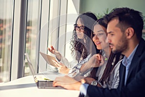 Creative business team sharing laptop in office, watching startup presentation, brainstorming, pointing at monitor