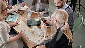 Creative business team at the table in a modern startup office. Female leader explains the details of the project.