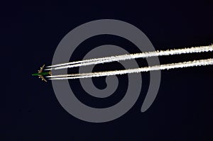 Creative capture of Aeroplane flying in a dark sky with white trail from jet engine
