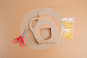 Creative cardboard crafting: plastic bag filled with yellow liquid next to brown paper cardboard pitcher, next to red
