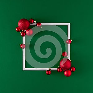 Creative Christmas baubles decoration with frame on green background. Minimal flat lay.