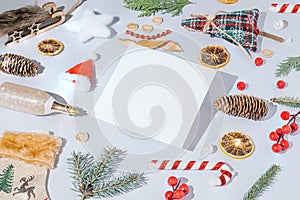 Creative Christmas composition with holiday decorations and white paper card on a gray background. Trendy New year template