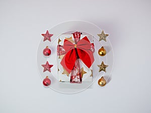 Creative Christmas composition made of gift box with red ribbon and baubles, christmas decorations, gold and red, flat lay, top vi