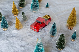 Creative Christmas decoration with red truck and colorful snowy spruces in the snow. Winter forest. Aerial, top view. Flat lay.