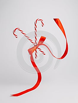 Creative Christmas layout made with flying candy canes with red ribbon on bright white background