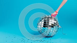 Creative Christmas party composition with doll leg in high heels and shiny disco ball on blue background. Minimal Xmas or New Year
