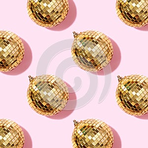 Creative Christmas pattern. Shiny gold disco balls over pink background. Flat lay, top view. New year baubles, star