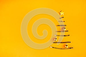 Creative Christmas tree made of wooden sticks. Minimal design on golden orange background.