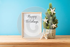 Creative Christmas tree with starfish decoration and frame mock up on wooden table over blue background