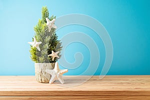 Creative Christmas tree with starfish decoration on wooden table over blue background