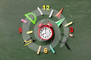 Creative clock face from colorful school supplies on blackboard top view and flat lay. Back to school concept.