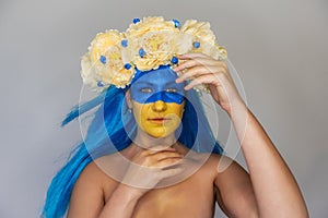 Creative close-up portrait of young Ukrainian patriot woman with yellow blue face art. Flag Day