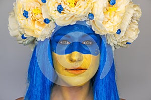 Creative close-up portrait of young woman with yellow blue face art. Concept for Flag Day in Ukraine