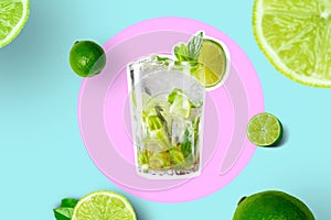 Creative Collage Of Glass With Mojito With Lime Slices And Limes on Bright Pink and Vivid Blue Geometric Background