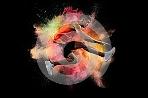 Creative collage of young man, professional athlete, runner training isolated over colorful powder explosion on black