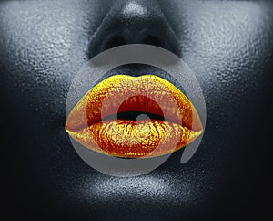 Creative colorful makeup. Bodyart, lipgloss on sexy lips, girls mouth. Golden lips on black skin