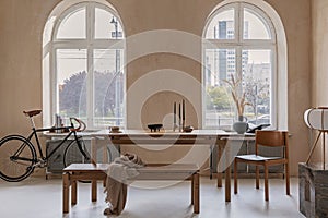 Creative composition of dining room interior design with wooden family table, armchair, bike and minimalistic home decorations.