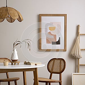 Creative composition of dining room interior with round table, rattan chair, wooden commode, pock up poster and kitchen