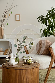 Creative composition of easter living room interior with boucle armchair, round pillow, vase with leaves, easter bunny, coffee