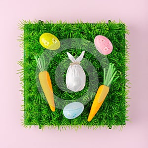 Creative composition with egg wrapped in a paper in the shape of a bunny with colorful Easter eggs. Easter minimal background.