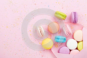 Creative composition with envelope and cake macaron or macaroon on pink pastel background top view. Flat lay.