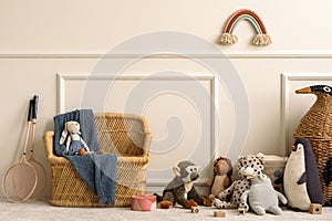 Creative composition of kids room interior with wicker basket, plush animal toys, plaid, wooden blockers, ornament on wall, beige