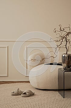 Creative composition of living room interior with copy space, white sofa, chrom vase with branch, glass coffee table, round rug, photo
