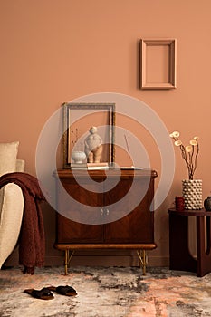 Creative composition of living room interior with frame, wooden sideboard, beige sofa, patterned carpet, round coffee table,