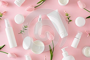 Creative composition made of cosmetic tubes without label, serum bottles, cream jars and spring flowers