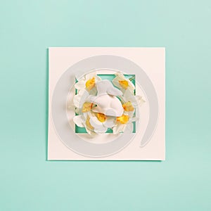 Creative composition made of easter bunny and flowers on pastel background with white frame. Minimal holiday concept