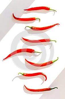 Creative composition made of red chilli peppers on white sunlit background with shadow. Healthy food ingredient concept. Flat lay