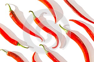 Creative composition made of red chilli peppers on white sunlit background with shadow. Healthy food ingredient concept. Flat lay