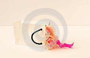 Creative composition made of white paper bag with girl legs in high pink heels and roses on bright background.