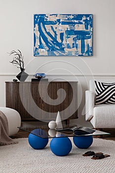 Creative composition of modern living room interior with mock up poster frame, stylish glass coffee table, blue pillow, boucle