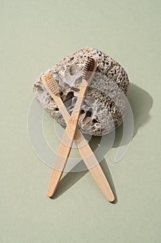 Creative composition with natural bamboo toothbrushes with stone on green background
