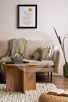 Creative composition of stylish living room with beige sofa, pillow, wooden coffee table, mock up poster frame, black tea pot,