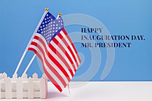 Creative composition with USA flags on white table with blue wall background, copyspace for text. Happy Inauguration Day wishes