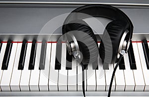 Creative concept of a digital piano keyboard with big black leather headphones