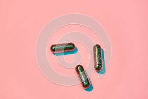 Creative concept with green glitter pills isolated on pastel pink background. Minimal style, art concept
