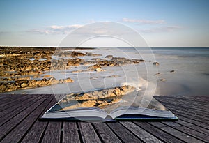 Creative concept pages of book Long exposure landscape rocky shoreline at sunset