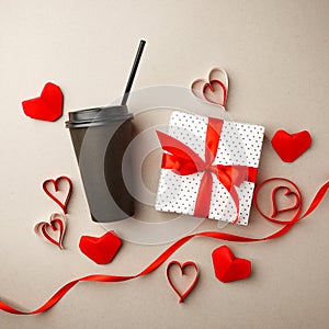 Creative concept photo of black stylish take away coffee cup with gift box red ribbon and frame from red origami paper hearts,