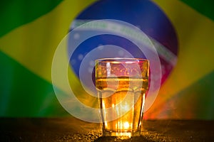 Creative concept. Pint of fresh beer on grass with blurred flag of Brazil on background or Glass of lager beer ready for drink. Co