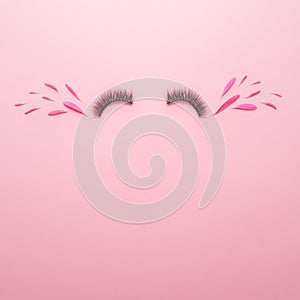 Creative concept of spring on a pink background. Glued on eyelashes with tears of joy from flower petals