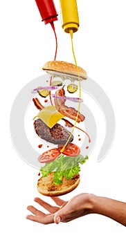 Creative cooking of hamburger. Flying ingredients, mustard and ketchup splashes