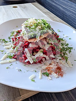 Creative cuisine - fresh beetroot risotto served with pan friend salmon fillet and parmesan crust