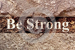 Creative design of bright style English text Be Strong isolated on old weathered rock wall background, strong of mind