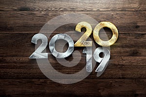 Creative design, Happy New Year, Metallic and gold numbers. Year 2019 is changing to 2020 Design on a wooden background. Merry