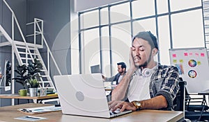 Creative designer slap face when sleepy while working hard with laptop at modern office.workplace lifesyle concept