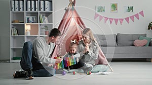 creative development of children, loving parents have fun with little girl playing musical instruments while sitting on